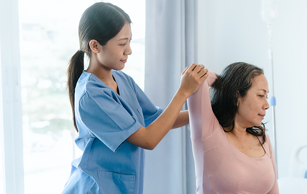 Female-Chiropractor-Wearing-Blue-Uniform-Adjusting-Female-Patients-Arm-NoFrills-Chiropractic-Singapore