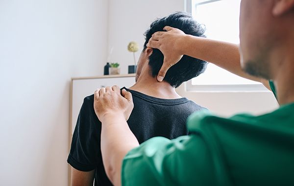 Green-Uniform-Chiropractor-adjusting-Male-Patients-Neck-sitting-down-NoFrills-Chiropractor-Singapore
