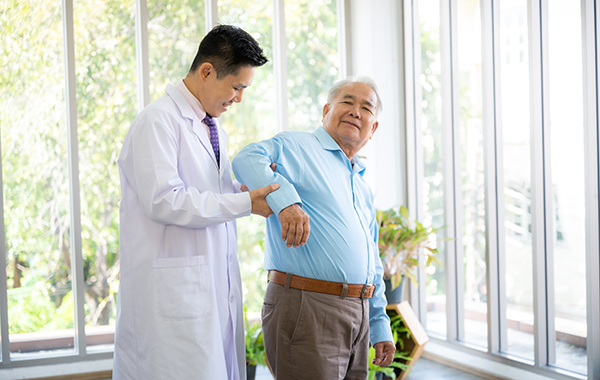 Male-Chiropractor-Supporting-Elderly-Man-Walking-NoFrills-Chiropractic-Singapore