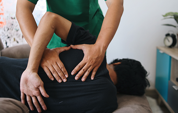 Male-Patient-Lying-Back-Face-with-Chiropractor-Placing-Hands-on-the-patients-Back-NoFrills-Chiropractic-Singapore