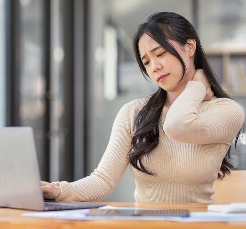 Women-Sitting-Down-Holding-her-Pain-Neck-While-Using-Laptop---NoFrills-Chiropractic-Singapore Women-Sitting-Down-Holding-her-Pain-Neck-While-Using-Laptop-NoFrills-Chiropractic-Singapore