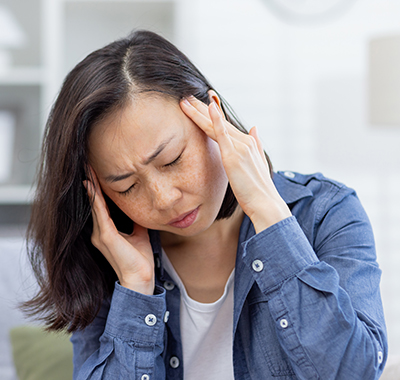 Asian-woman-having-migraine-NF-Chiropractic Female-Chiropractor-adjusting-White-T-shirt-Male-Patients-Arm-NoFrills-Chiropractic-Singapore