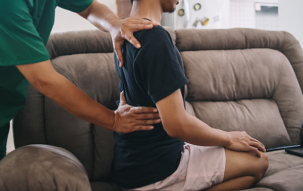 Male-Chiropractor-adjusting-Elderlys-Back-Side-Ways-in-Homebase-NoFrills-Chiropractic-Singapore