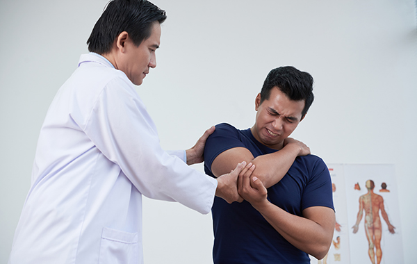 Male-chiro-assess-male-patient-arm-NF-Chiropractic NoFrills-Dental-Chriopractor---Female-Chiro-adjusting-male-patient- Chiropractic Singapore