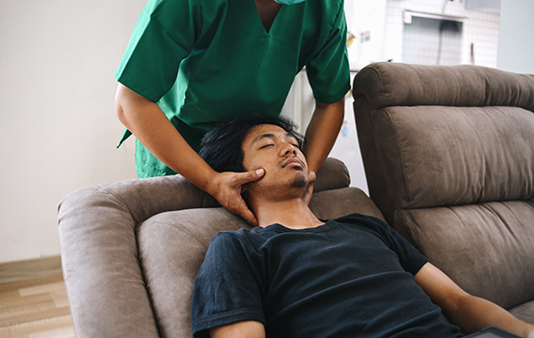 Male-Chiropractor-adjusting-Elderlys-Back-Side-Ways-in-Homebase-NoFrills-Chiropractic-Singapore