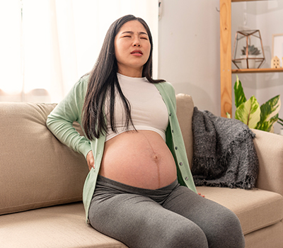 Pregnant-lady-on-sofa-NF-Chiropractic Pregnant Lady suffering for sciatica back pain